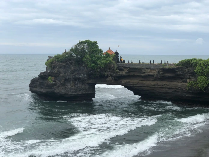brown rock formation on sea under white clouds during daytime